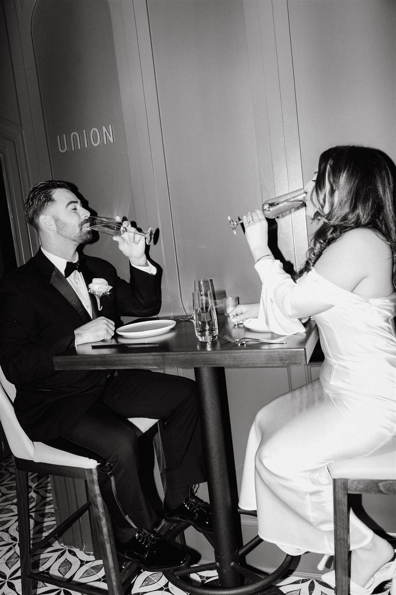 creative black and white flash photo of bride and groom drinking champagne